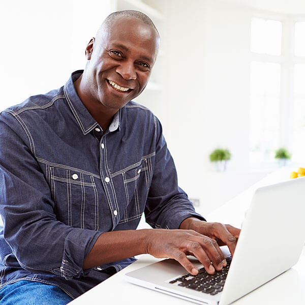 Man Smiling While Working on a Laptop Computer