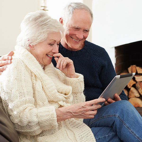 Older Couple Smiling While Looking at a Tablet Computer