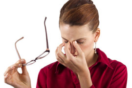 Woman experiencing eye strain while holding her glasses off her face